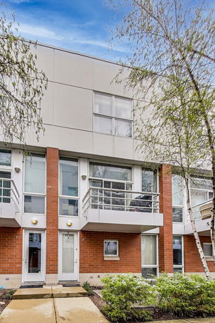 Front view of a multi-story modern townhouse with brick and panel facade.