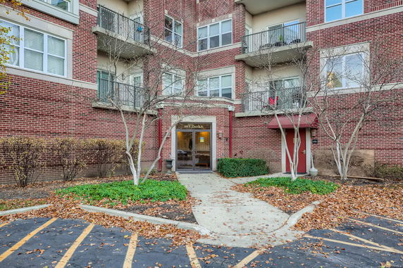 Front view of a multi-story brick building with balconies and entrance.