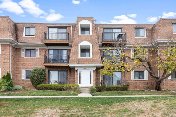 Front view of a multi-story brick apartment building with balconies.