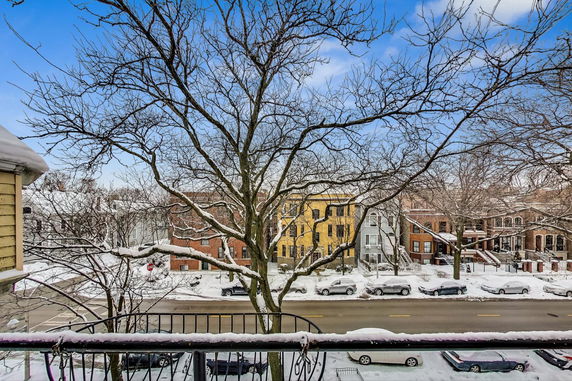 Wide-angle view of a street lined with houses during winter, seen from a higher vantage point. Snow covers the ground and trees.