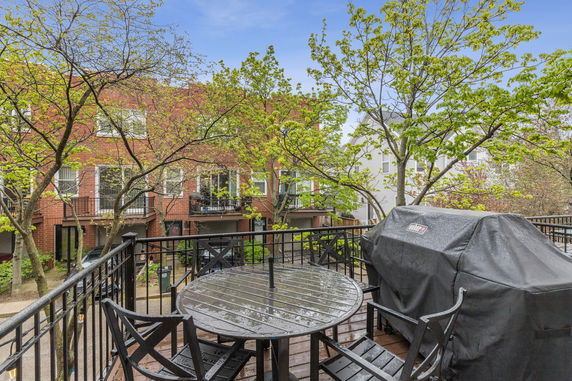 View of surrounding area from an outdoor patio with furniture and a covered grill.