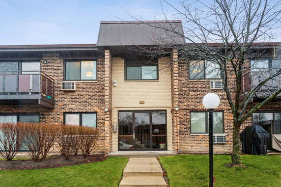 Front view of a two-story brick apartment building with multiple windows and balconies.