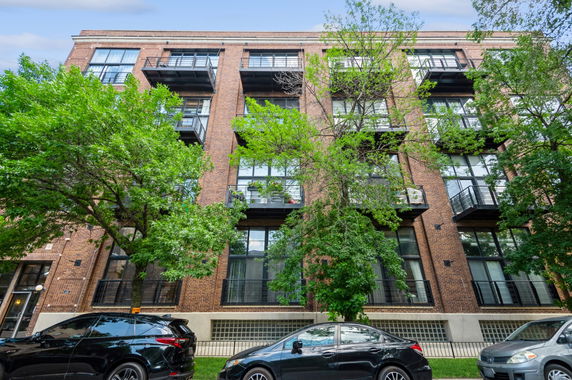 Front view of a multi-story brick apartment building with balconies.