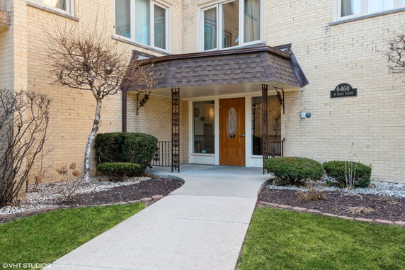 Front view of a multi-story building with a doorway entrance and small landscaped area.