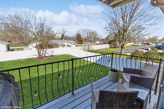 View of surrounding residential area from a balcony with chairs and a table.