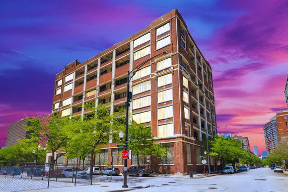Front view of a multi-story brick building with large windows.