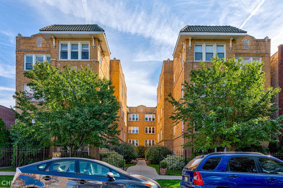 Front view of a multi-story apartment building with a central courtyard.