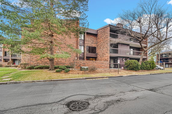 Front view of a three-story brick apartment building with balconies.