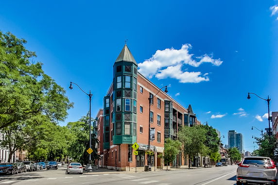 Front view of a multi-story brick building with a unique corner turret feature.