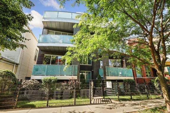 Front view of a modern multi-story building with glass balconies.