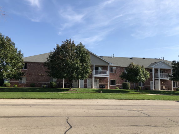 Front view of a two-story apartment building with brick exterior and covered balconies.