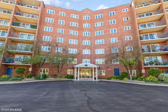 Front view of a multi-story brick apartment building with multiple balconies.