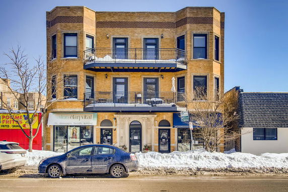 Front view of a three-story building with a symmetrical facade and two balconies on the second and third floors.