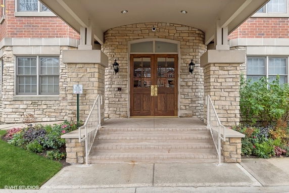 Entrance of a building with stone and brick facade and wooden doors.