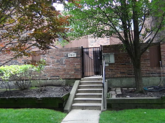 Front view of a brick building with a gated entrance and steps leading up.