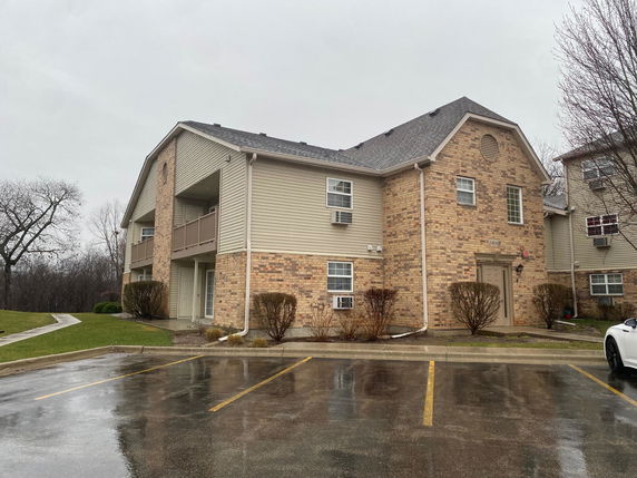 Front view of a two-story brick and siding residential building with a parking area.