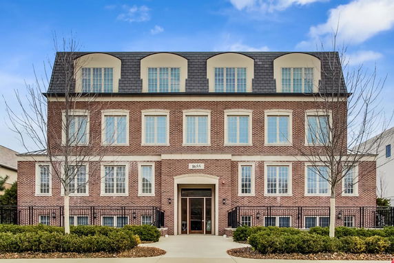 Front view of a multi-story brick building with large windows and a central entrance.