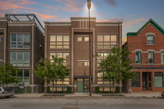 Front view of a multi-story brick building with large windows and a central entrance.