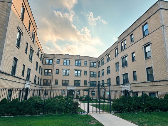 Front view of an apartment building with multiple floors and a courtyard entrance.