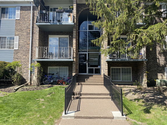 Front view of a brick apartment building with balconies and a central entrance.