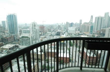 Panoramic view of a cityscape from a high-rise building balcony with visible skyscrapers.