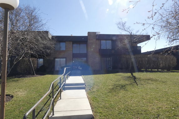 Front view of a two-story building with large windows and a paved walkway leading to the entrance.