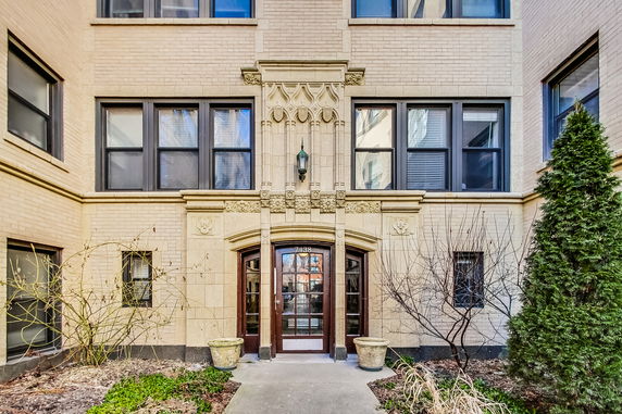 Front view of a multi-story apartment building entrance with decorative brickwork.