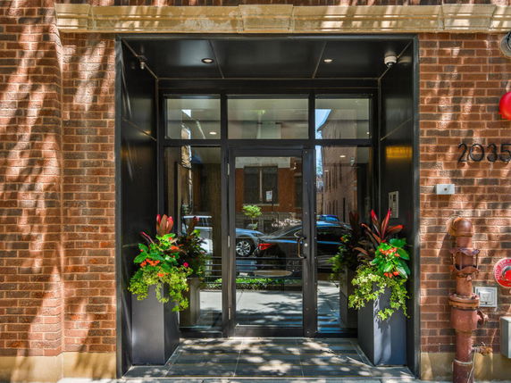 Front view of a building entrance with glass doors and brick facade.