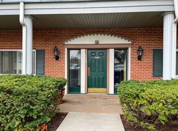 Front view of a brick building with a green door and white columns.