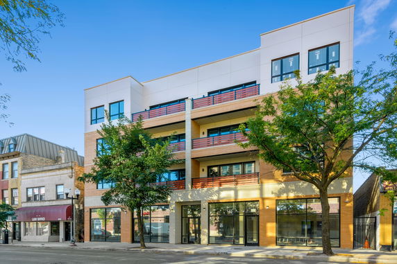 Front view of a modern multi-story building with large windows and balconies.