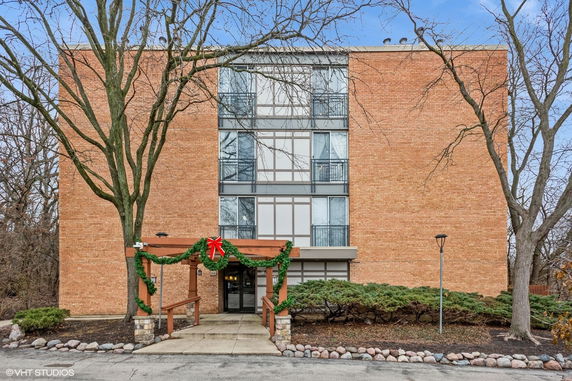 Front view of a multi-story brick building with large windows and a decorated entrance.