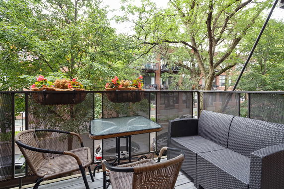 Balcony with patio furniture overlooking trees and surrounding buildings.
