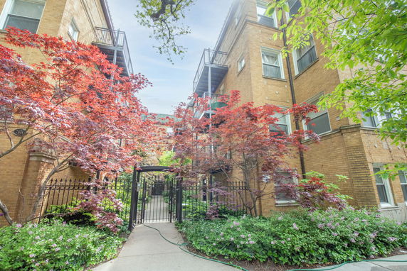 Front view of a multi-story brick apartment building with balconies and a gated entrance.