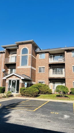 Front view of a brick apartment building with multiple balconies and windows.