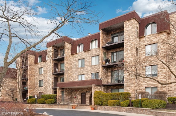 Front view of a multi-story brick apartment building with balconies and a main entrance.