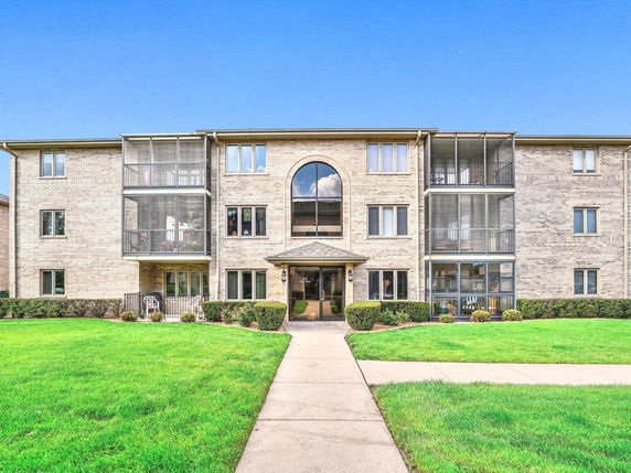 Front view of a multi-story brick apartment building with balconies.