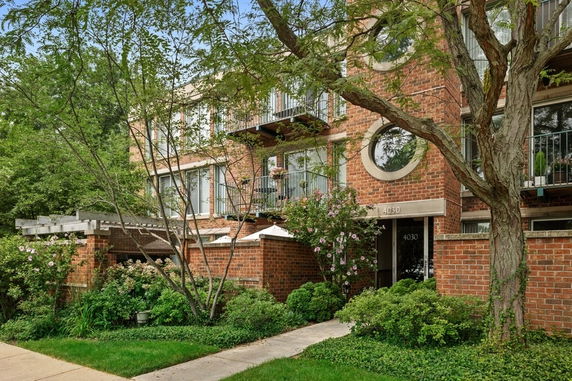 Front view of a multi-story brick building with balconies and circular windows.