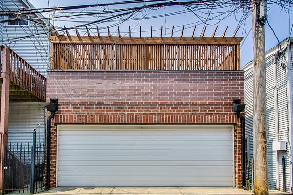 Front view of a brick building with a garage and rooftop fence.