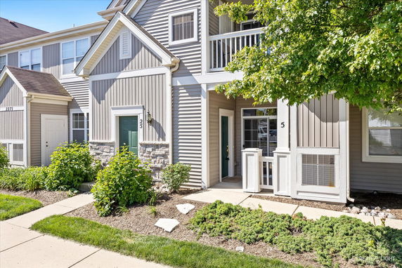 Front view of a two-story townhouse with beige siding and a small balcony.