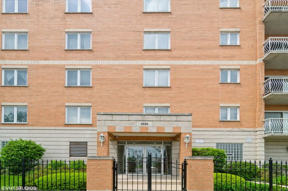 Front view of a multi-story brick building with gated entrance.