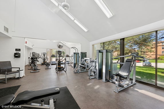 Interior view of a gym with various exercise machines and large windows.