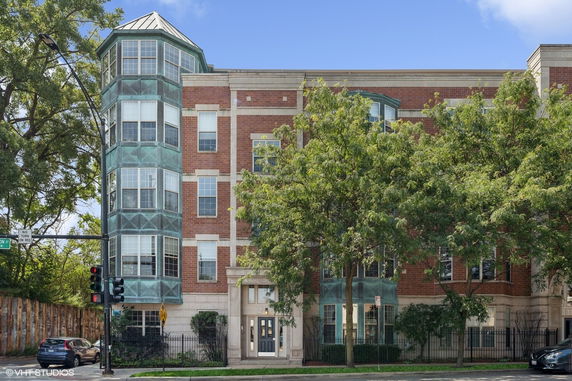 Front view of a multi-story brick building with large windows and a distinct corner architectural feature.