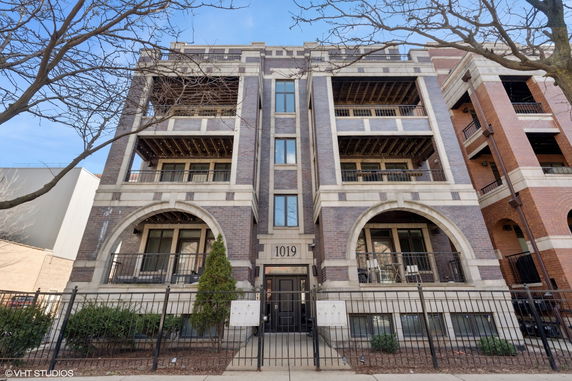Front view of a multi-story residential building with balconies and arched design elements.