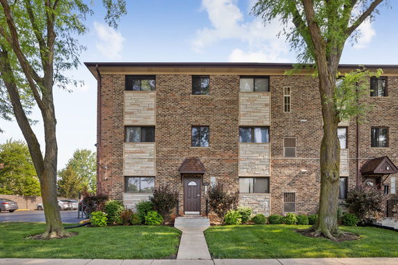 Front view of a multi-story brick apartment building with several windows.