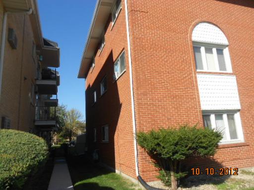 Side view of a two-story brick apartment building with white windows.