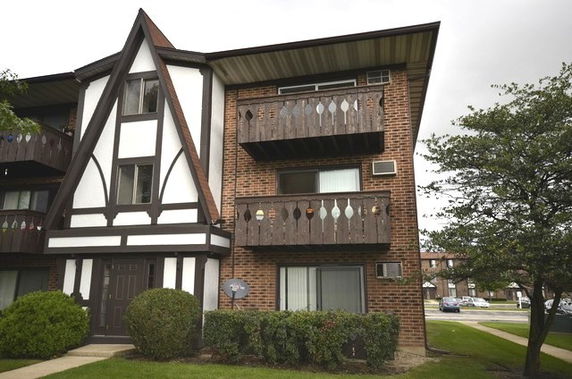 Front view of a two-story residential building with brick facade and wooden balconies.