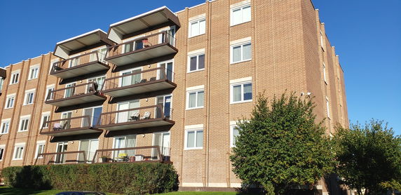 Front view of a multi-story brick apartment building with balconies.