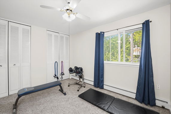 Room with exercise equipment including a bench, dumbbells, and resistance bands.