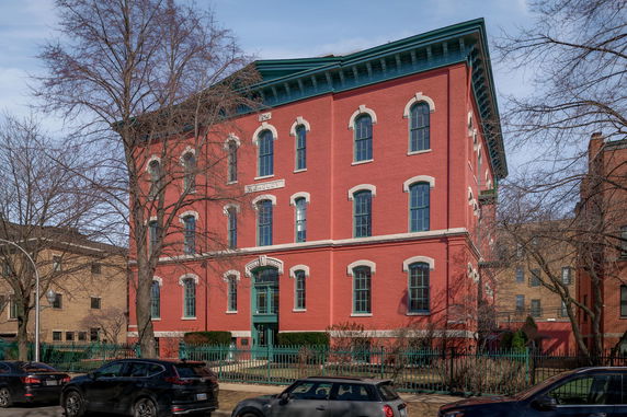 Front view of a three-story red brick building with large windows and a central entrance.