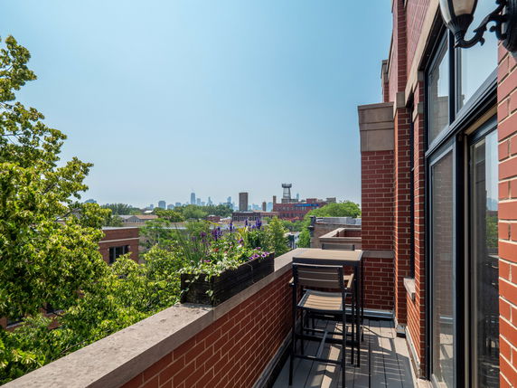 Panoramic view of urban skyline from a balcony with red brick wall.